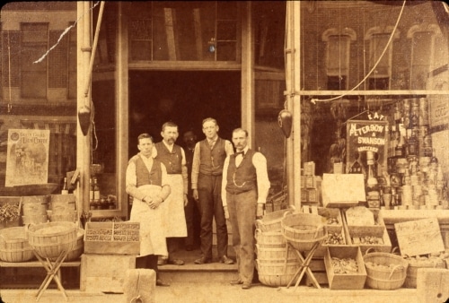 Men pose in front of grocery store
