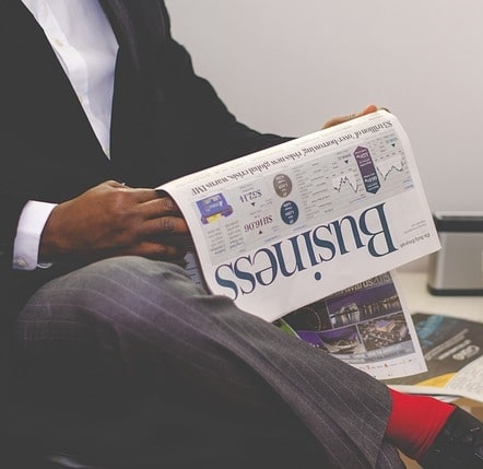 man in suit reading business section of newspaper