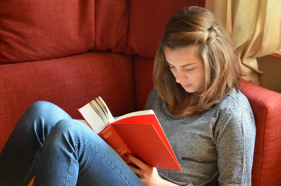 teen girl reading a book on couch